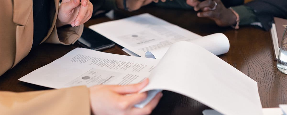 Mãos revisando documentos sobre uma mesa de reunião